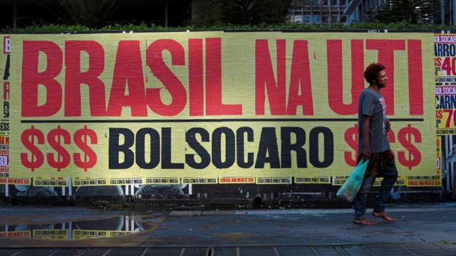 Homem caminha descalço em frente a uma faixa que diz "Brasil na UTI, Bolsocaro" em São Paulo, Brasil, 8 de março de 2021