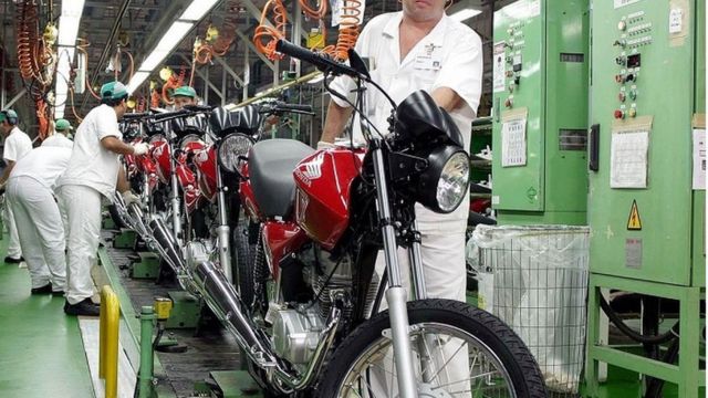 Operários e motocicletas em linha de produção da Honda
