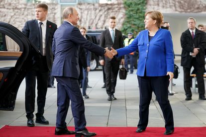 O presidente russo, Vladimir Putin, e a chanceler alemã, Angela Merkel, cumprimentam-se em Berlim, em janeiro de 2020, no início de uma conferência sobre a Líbia.