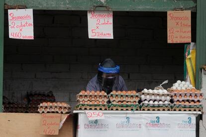 Uma mulher se protege da covid-19 na banca onde vende ovos, em Quito (Equador).